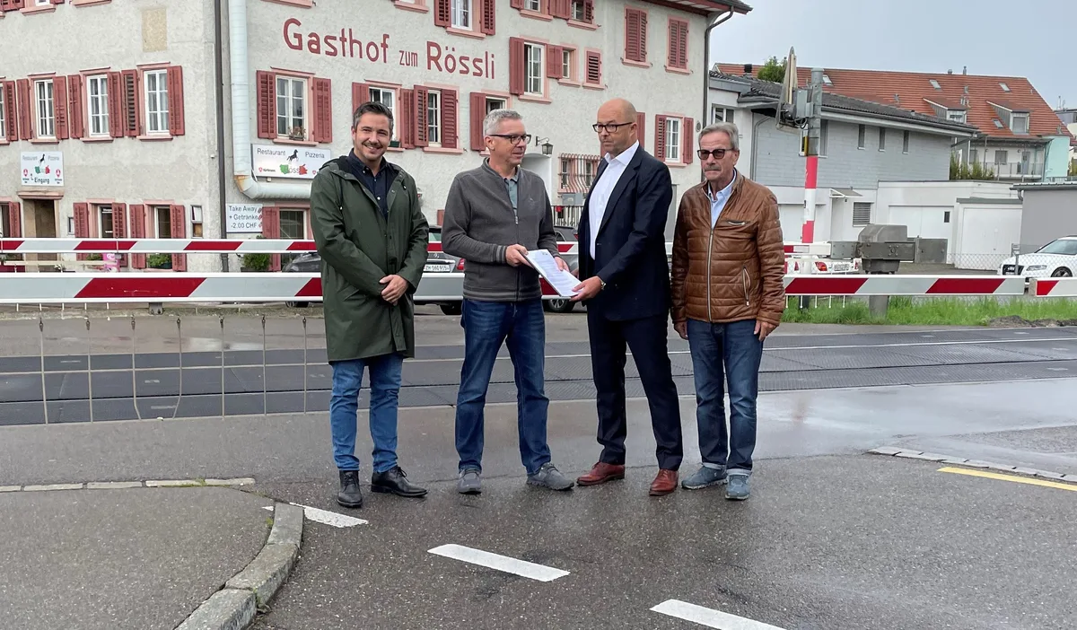 Auf dem Foto sieht man vier Männer vor einer Bahnschranke.